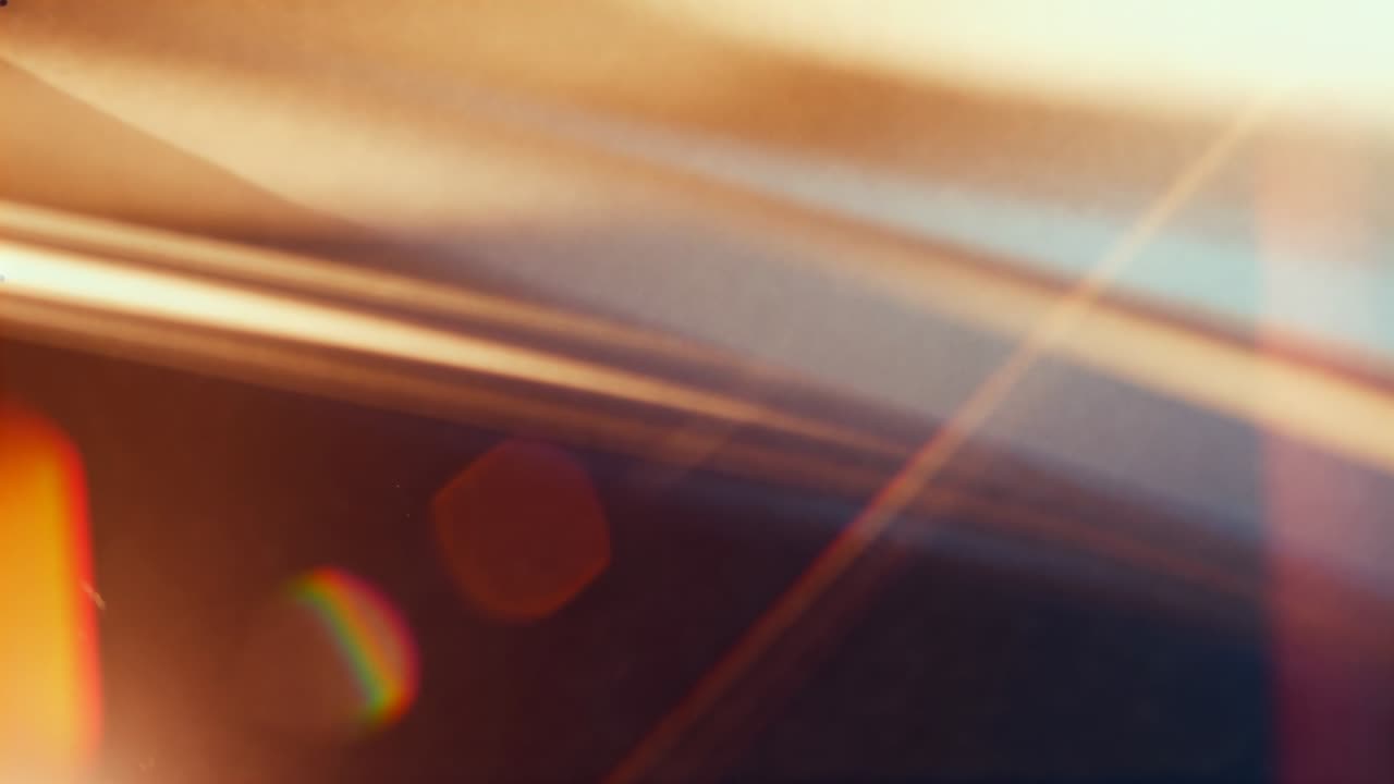 Shifting diagonal light band sliding across lens surface after camera shift, showing rainbow bokeh
