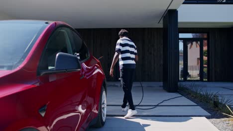 man charging electric car at home