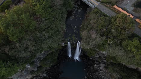drone aerial view in south korea flying over a waterfall falling into the sea rocky area jeju island