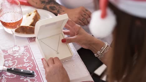 woman looking at a necklace into a box as christmas present