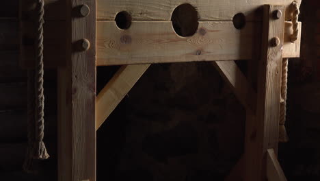 una picota está hecha de un marco de madera con agujeros para la cabeza y las manos, ubicada en una fortaleza