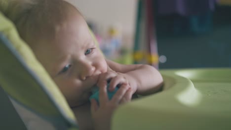 cute boy cries dropping bottle of water in green highchair