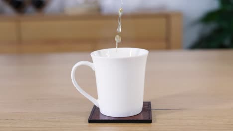 liquid being poured into a white mug on a coaster