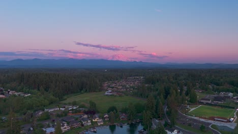 drone shot of a pink mt rainier with bonney lake's suburban neighborhoods underneath.