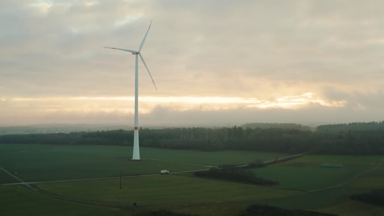 Car Driving by Wind Turbines at Sunset in Germany