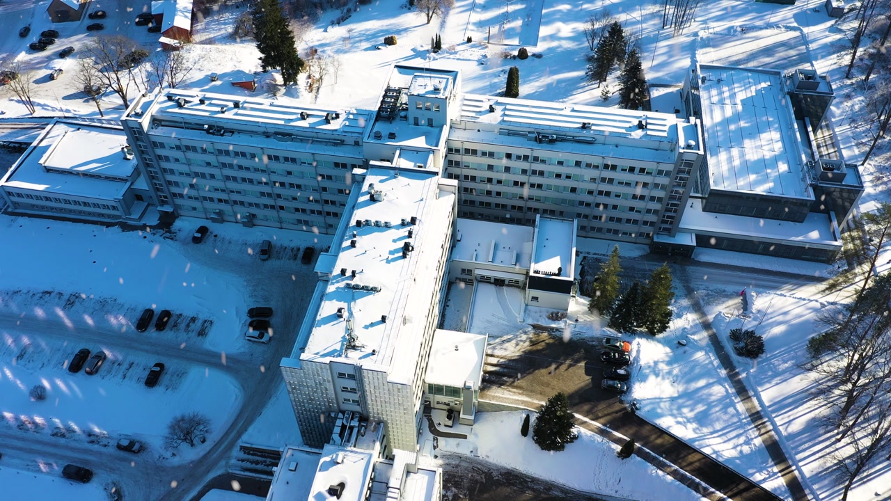 Hospital complex covered in snow, showcasing medical business facility in winter sunny day