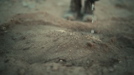 person watering an arid desert terrain in slow motion