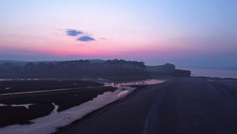 aerial drone rising pedestal shot of coastal beach seaside at twilight blue hour, england