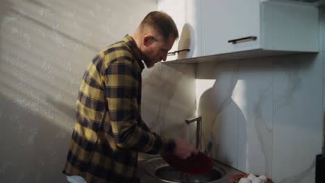 man washing dishes in kitchen