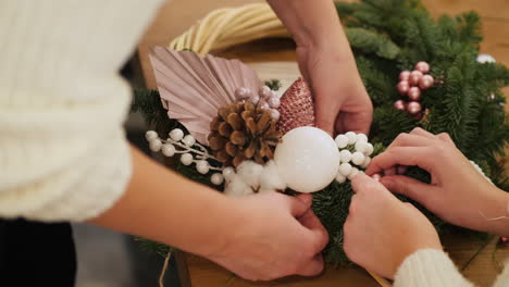 mujer con niño arregla joyas en corona de navidad 1
