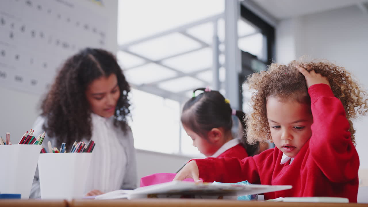 joven estudiante con uniforme trabajando en un escritorio en una clase de escuela infantil, de cerca, ángulo bajo