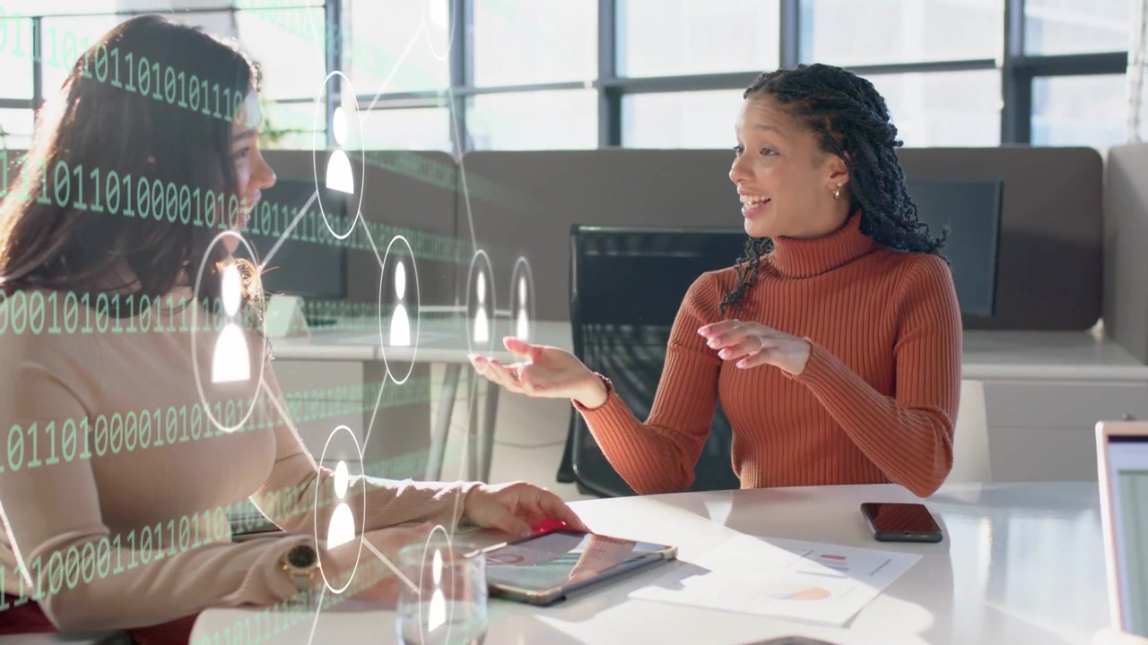 Left woman tapping tablet with red mouse, causing binary icons overlay while right talking for biz