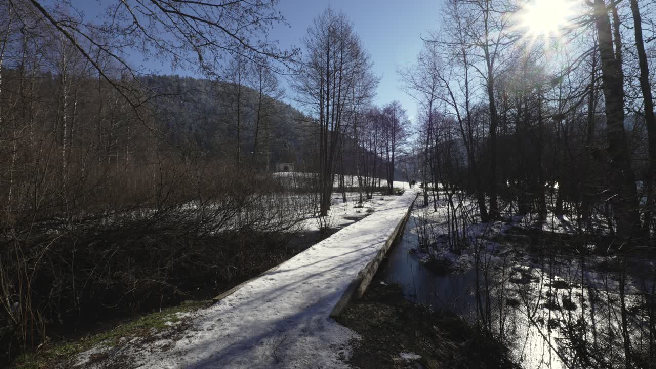 Vidvinkelbillede af en bro dækket af sne og is i et smukt skovlandskab i Vogeserne, Frankrig