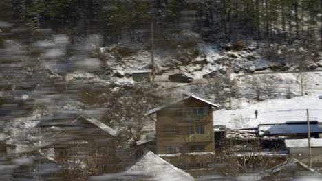 moving shot of a car passing by a snowy village