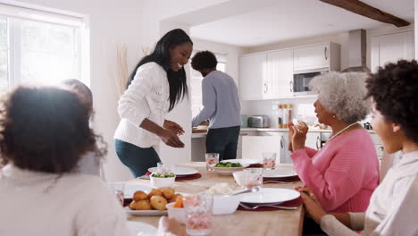 Ein-Hinteres-Pärchen,-Das-Bei-Einem-Sonntäglichen-Familienessen-Mit-Den-Kindern-Und-Ihren-Großeltern-Essen-Auf-Den-Tisch-Bringt