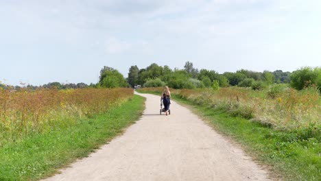 long blond hair mother walking baby stroller on breezy latvia rural path