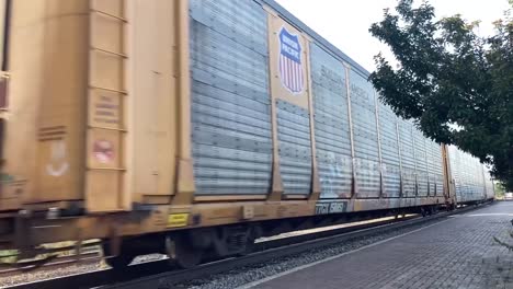 Large-cargo-train-flying-through-a-small-town-with-graffiti-painted-on-its-side