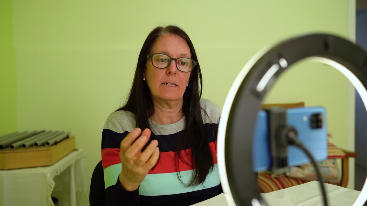 mujer madura dando reuniones informativas en línea en casa - medio