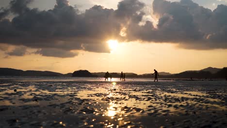 caucasian family playing on ao nang beach as the sun sets, spending time as a family on a vacation holiday to krabi thailand