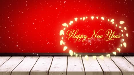 Animation-of-snow-falling-over-happy-new-year-text-over-fairy-light-banner-on-wooden-surface