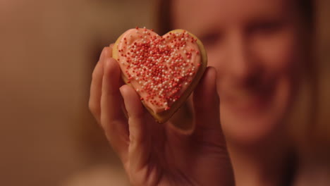 woman holding a heart-shaped cookie
