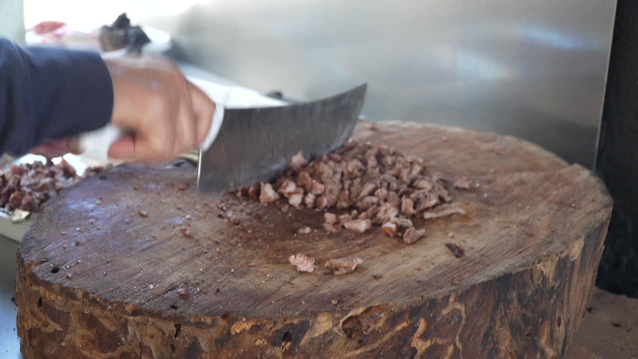 la carne asada es picada en una tabla de madera para hacer tacos