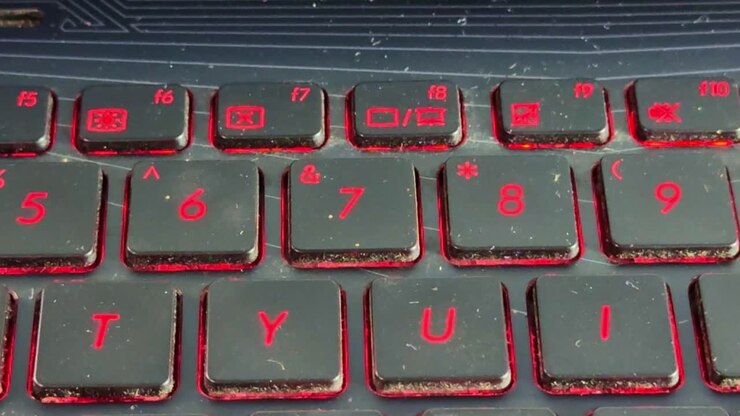 hand typing on laptop keyboard in 7, finger pressing keys in low light with glowing red backlight