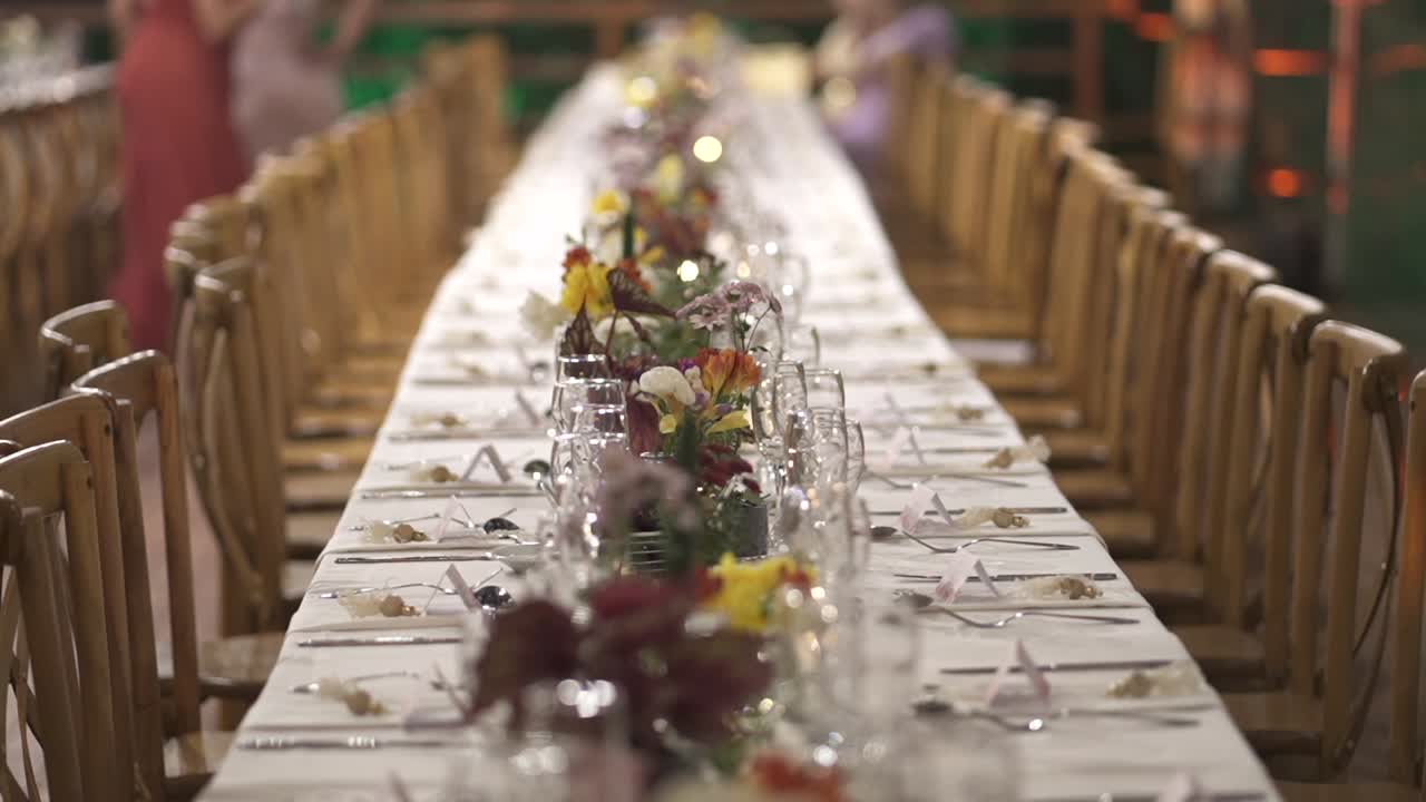 Elegant long dinner table set with candles and flowers prepared for wedding celebration