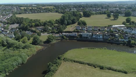 drone shot approaching a bend in the exe river on a sunny afternoon in devon, uk