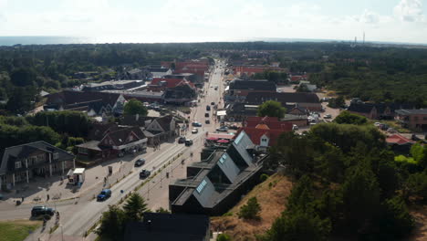 Backwards-fly-above-buildings-along-main-street-in-Oksby.-Aerial-view-of-small-town-near-sea-coast.-Summer-vacation-destination.-Denmark