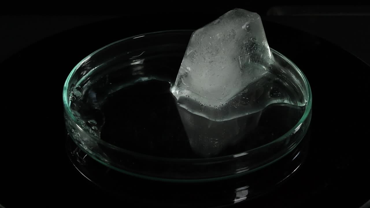secuencia que muestra un cubo de hielo derritiéndose en un plato de vidrio.