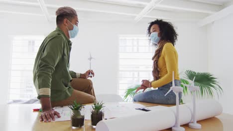 Office-colleagues-wearing-face-mask-discussing-and-taking-notes-at-office