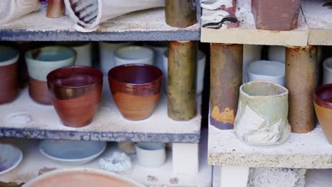 racks of cups, bowls and vases inside a pottery kiln awaiting finishing - left to right panning shot