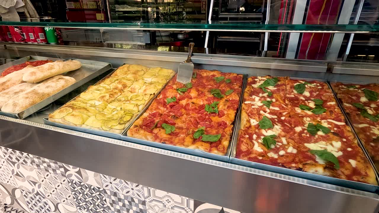 Várias pizzas expostas em uma vitrine de vidro