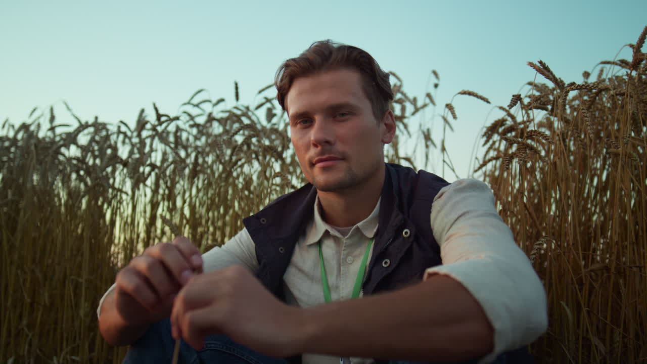 retrato de un granjero serio posando en un campo de trigo cultivado. un hombre cansado descansa solo.