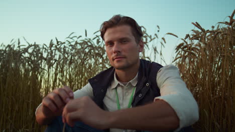 retrato de un granjero serio posando en un campo de trigo cultivado. un hombre cansado descansa solo.