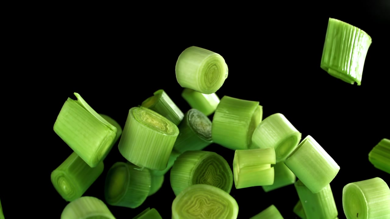 Chopped Green Onions Falling in Slow Motion on Black Background