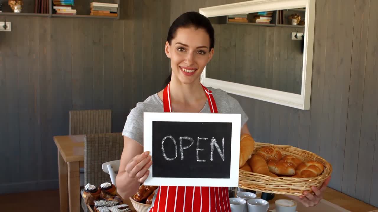 retrato de una panadera con baguettes y un cartel abierto