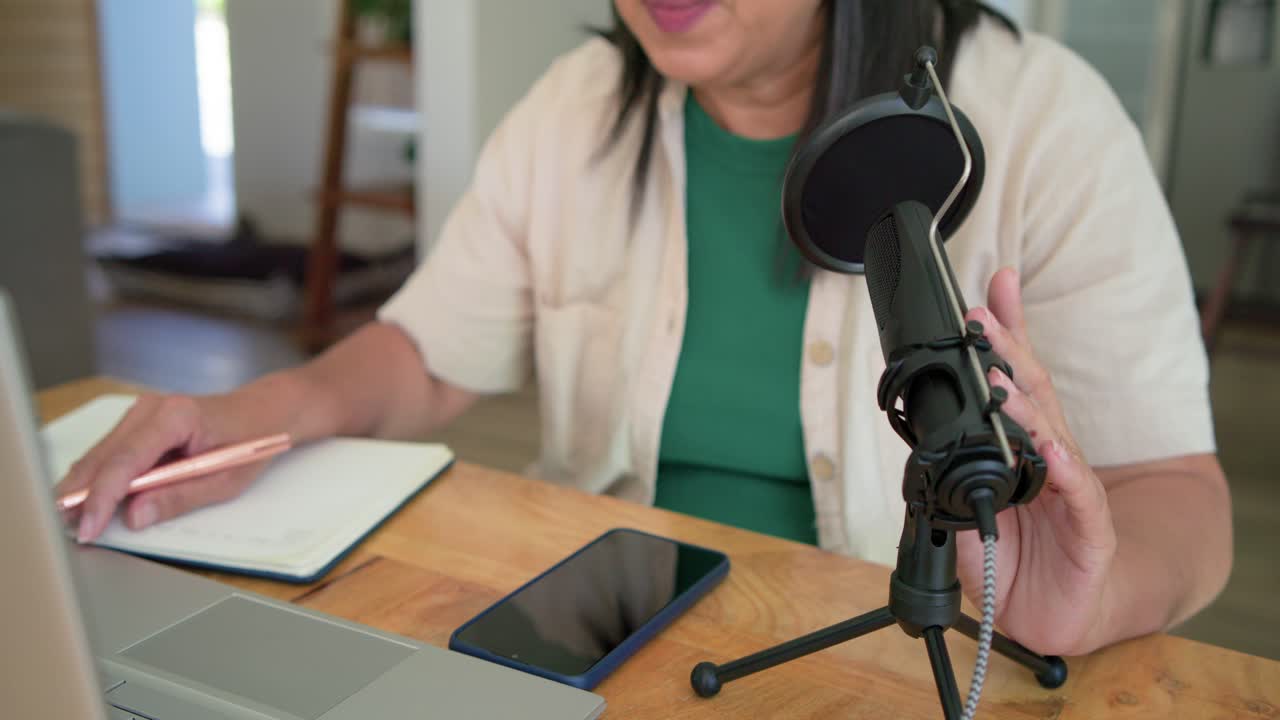 Premendo il trackpad per registrare, l'ospite sta regolando il microfono e ci parla dentro per un podcast al tavolo.