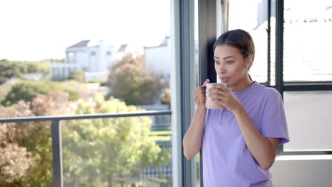 Drinking coffee, woman in purple shirt enjoying morning on balcony, copy space