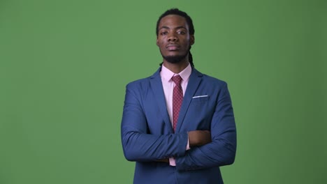 young handsome african businessman with dreadlocks against green background