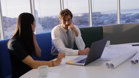 Front-view-of-young-Caucasian-office-executives-working-on-laptop-at-table-in-modern-office-4k