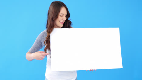 Beautiful-woman-holding-blank-placard-on-blue-background