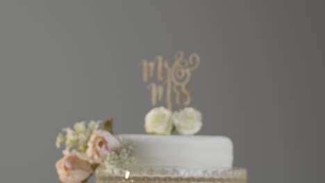 Primer-Plano-Del-Pastel-De-Bodas-En-El-Stand-Contra-El-Fondo-Gris-Del-Estudio-En-La-Recepción-De-La-Boda-3