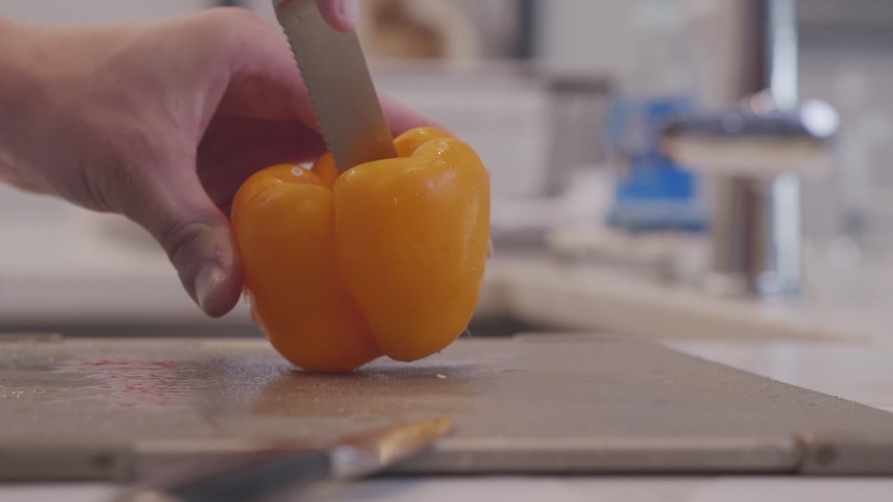 Slow motion footage of a Yellow Pepper cut into quarters in a modern kitchen