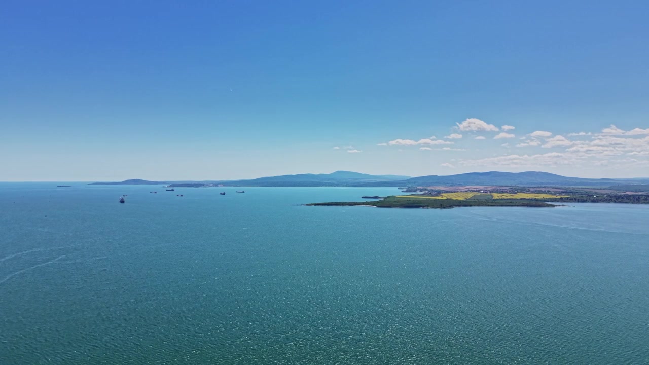 昼間の澄み切った青空の下、海と陸の色鮮やかな景色。