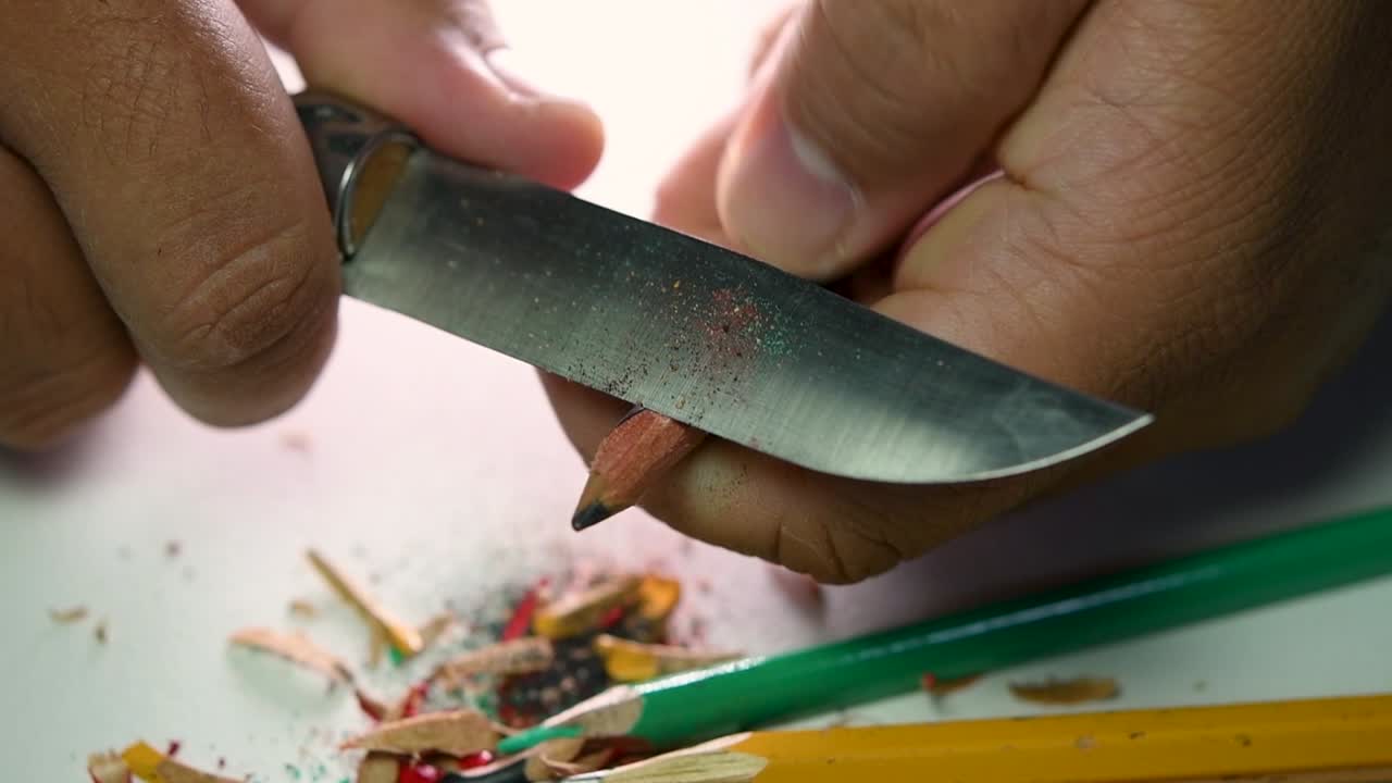 imágenes de manos afilando lentamente un lápiz y algunos lápices de colores con un cuchillo afilado