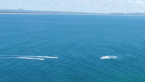 aerial view of boats and jet skis playing in the ocean