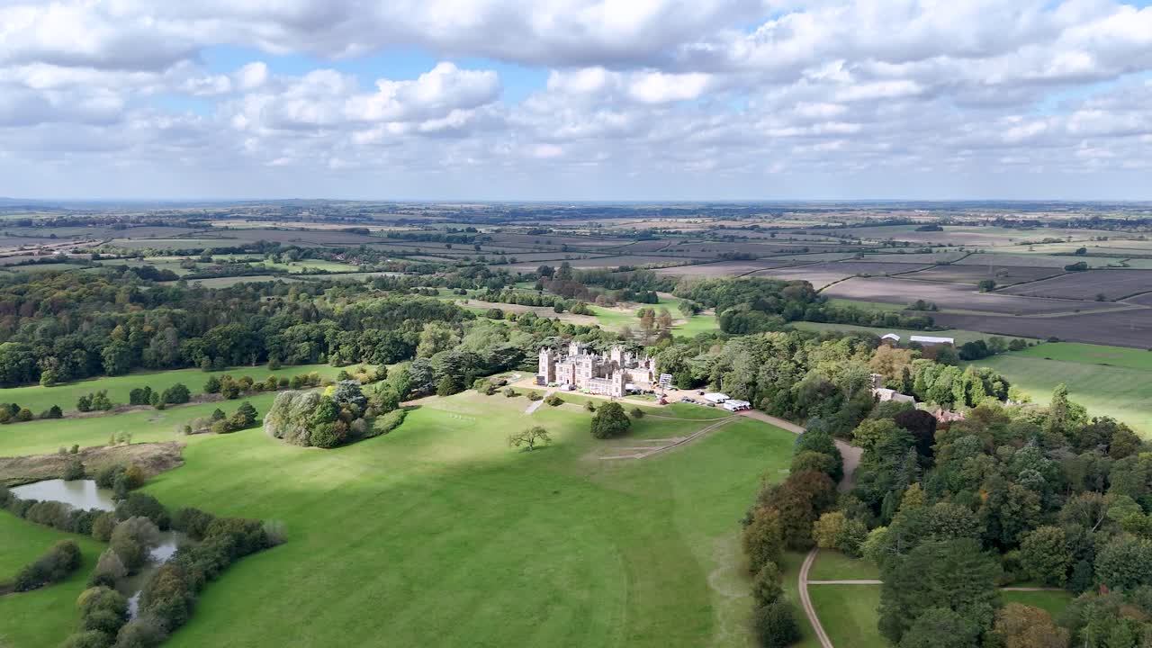 Aerial view following cloud shadow passing across majestic Mentmore towers country house estate