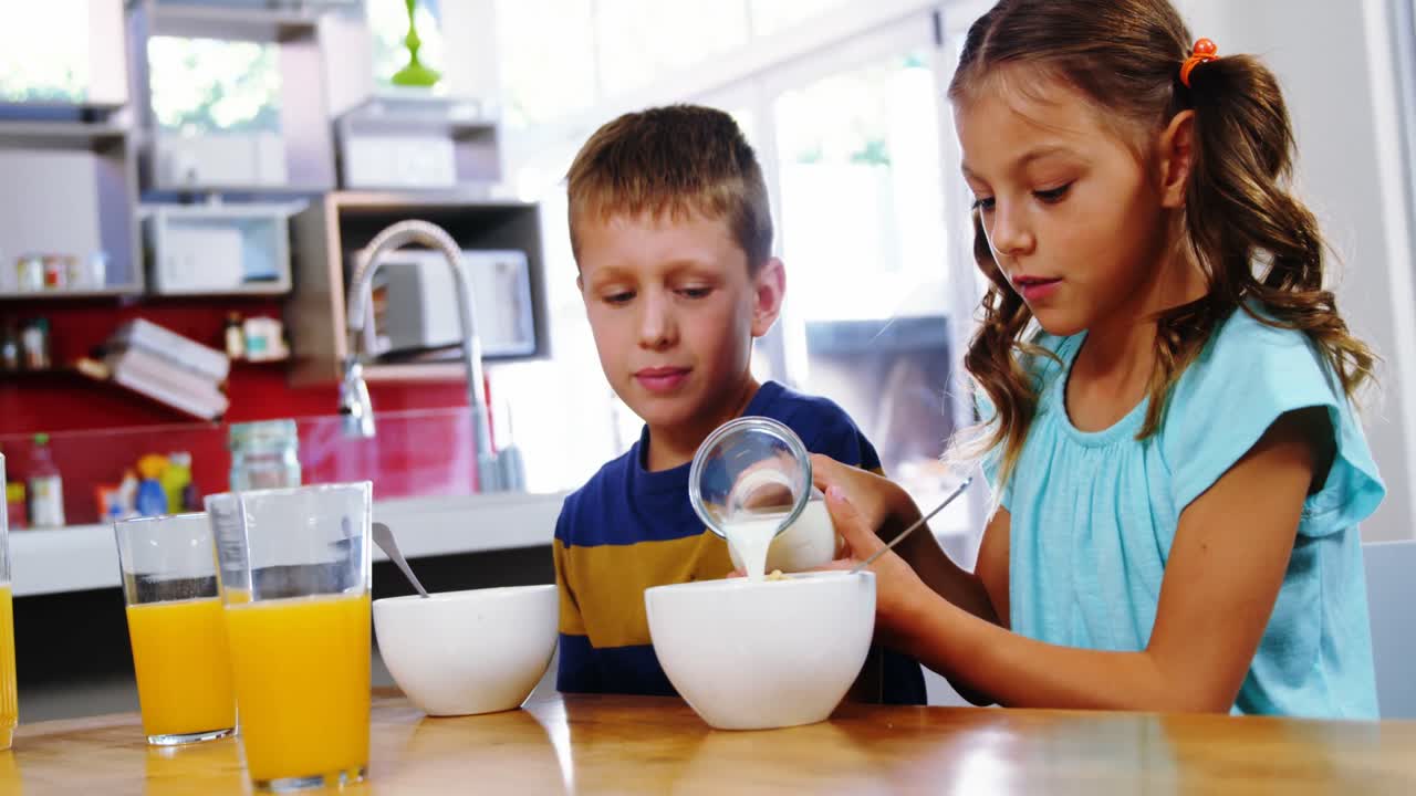 Ragazza che versa il latte nella ciotola dei cereali in cucina